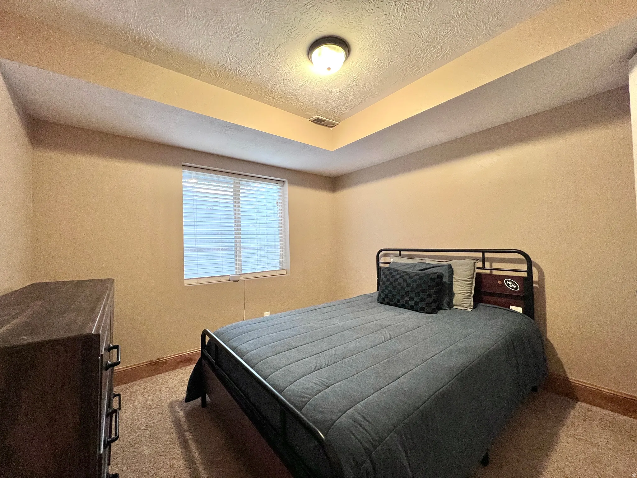 Bedroom featuring light carpet and a textured ceiling