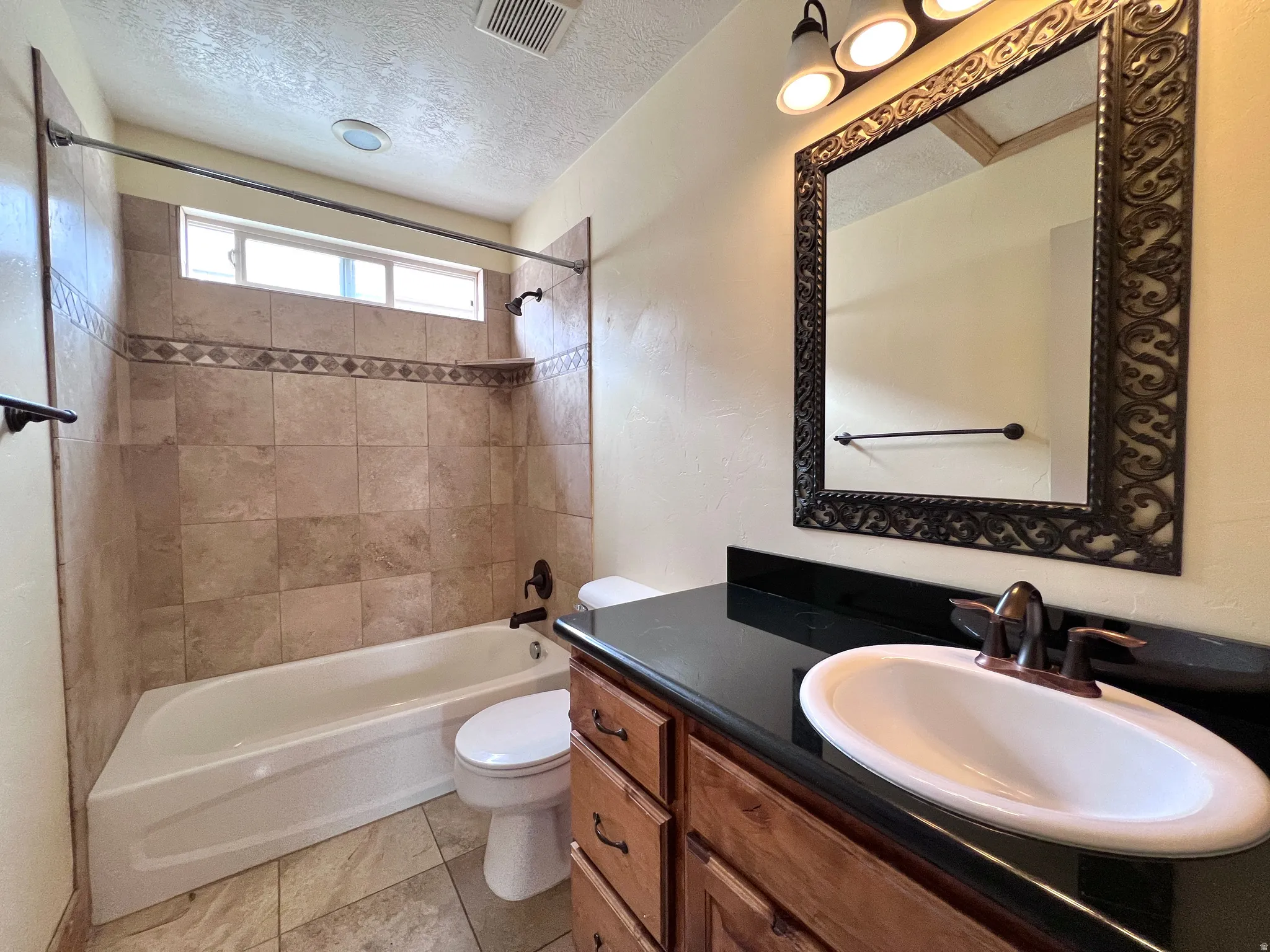 Full bathroom with vanity, a textured ceiling, and washtub / shower combination