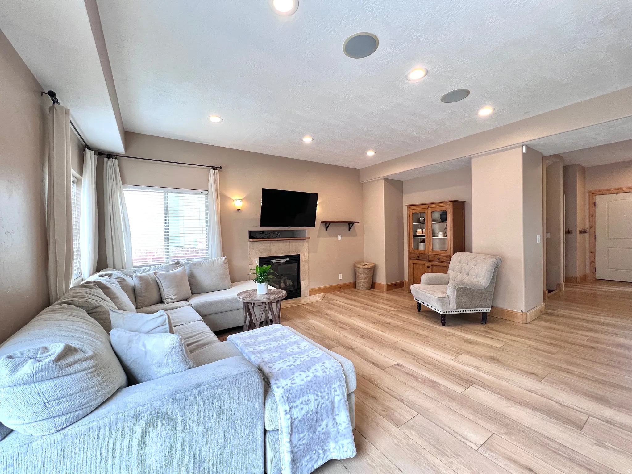 Living area with light wood finished floors, a fireplace, and recessed lighting