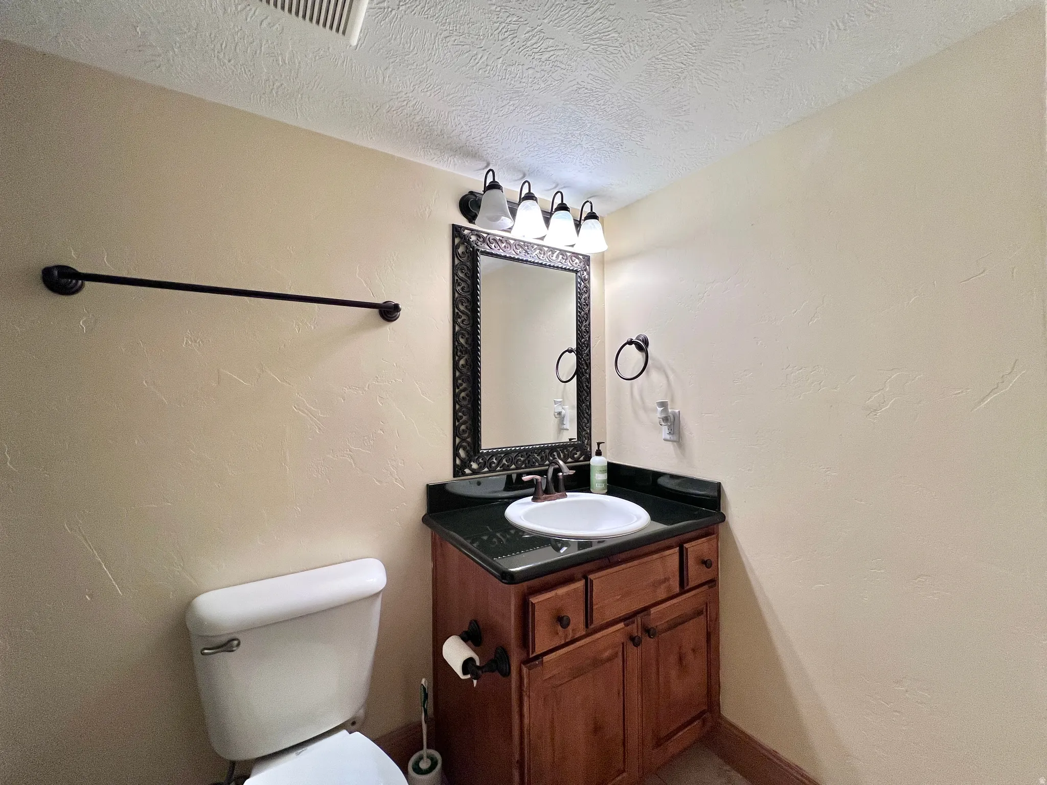 Bathroom featuring a textured wall, vanity, and a textured ceiling