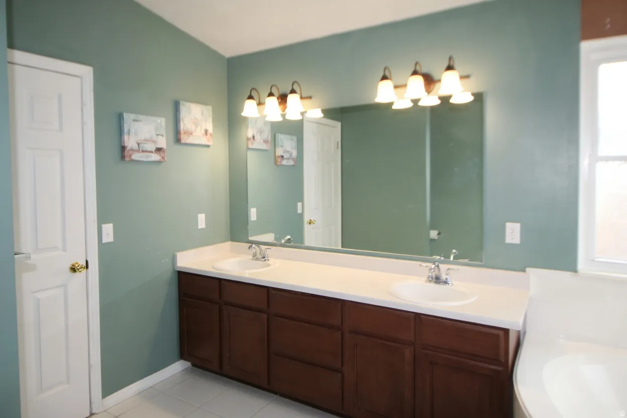 Bathroom featuring double vanity, light tile patterned flooring, and a garden tub
