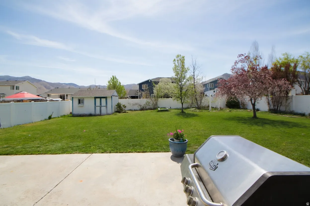 Fenced backyard with an outbuilding, a residential view, a patio, and a mountain view