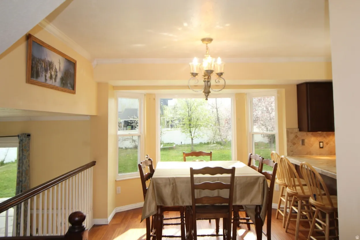 Dining room with ornamental molding, hanging lights, and light wood-type flooring
