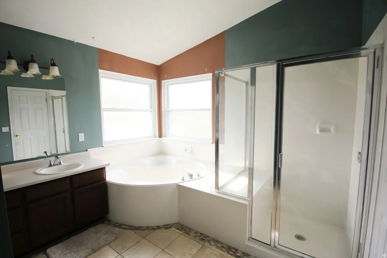 Full bathroom with vanity, a bath, a stall shower, light tile patterned floors, and lofted ceiling