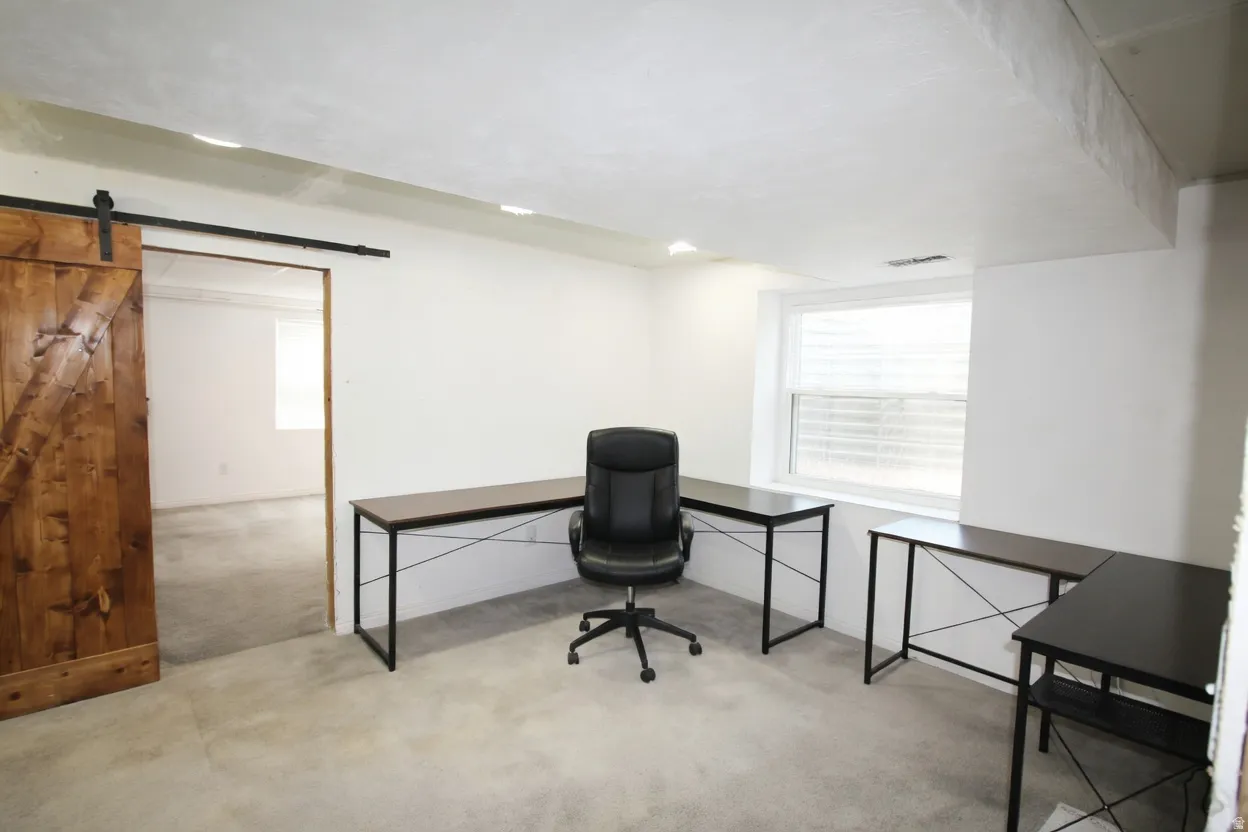 Office featuring a barn door and light carpet