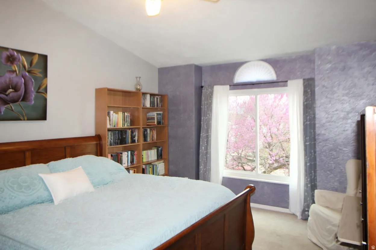 Bedroom with light carpet and lofted ceiling