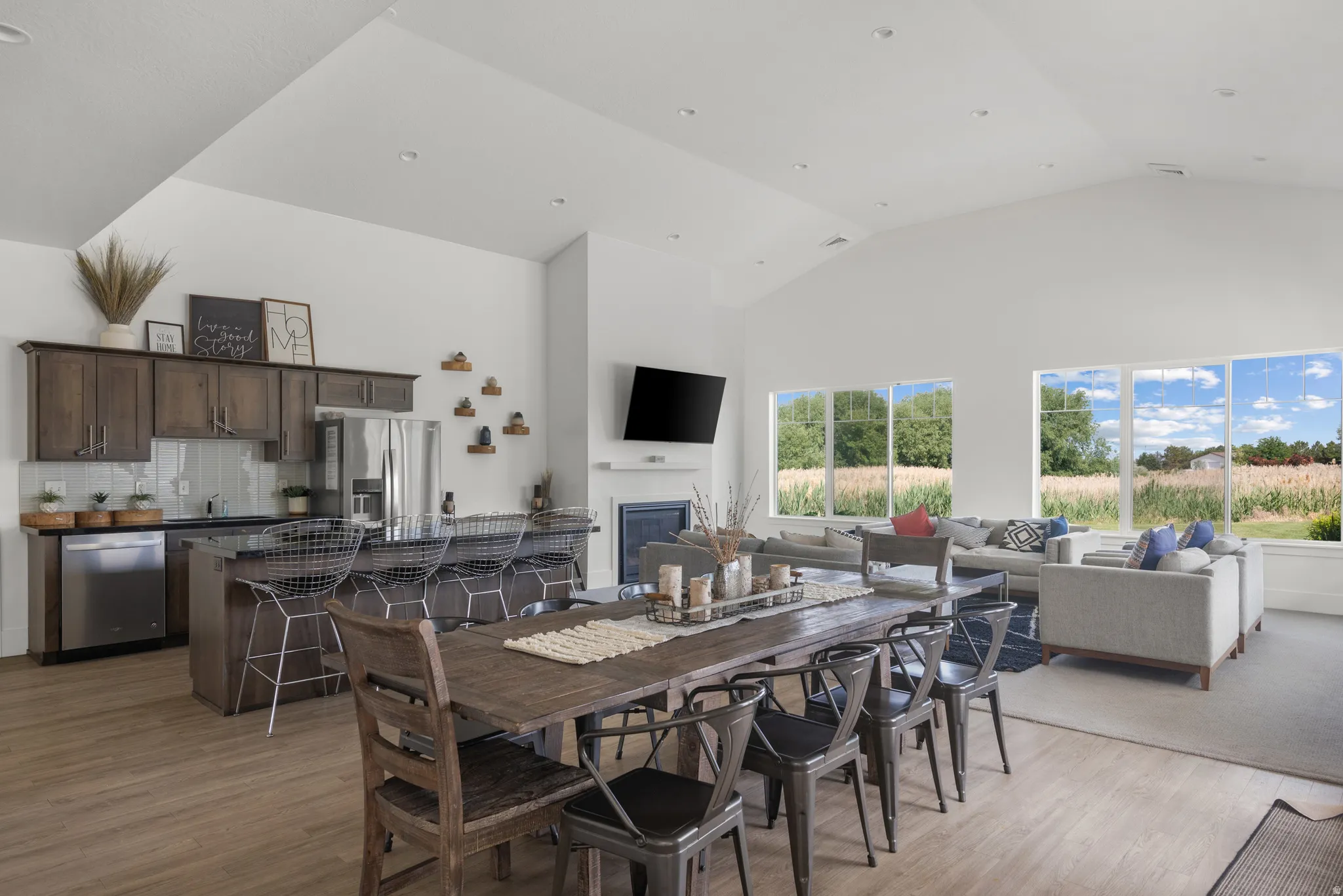 Dining space with a high ceiling, light wood-type flooring, and a glass covered fireplace