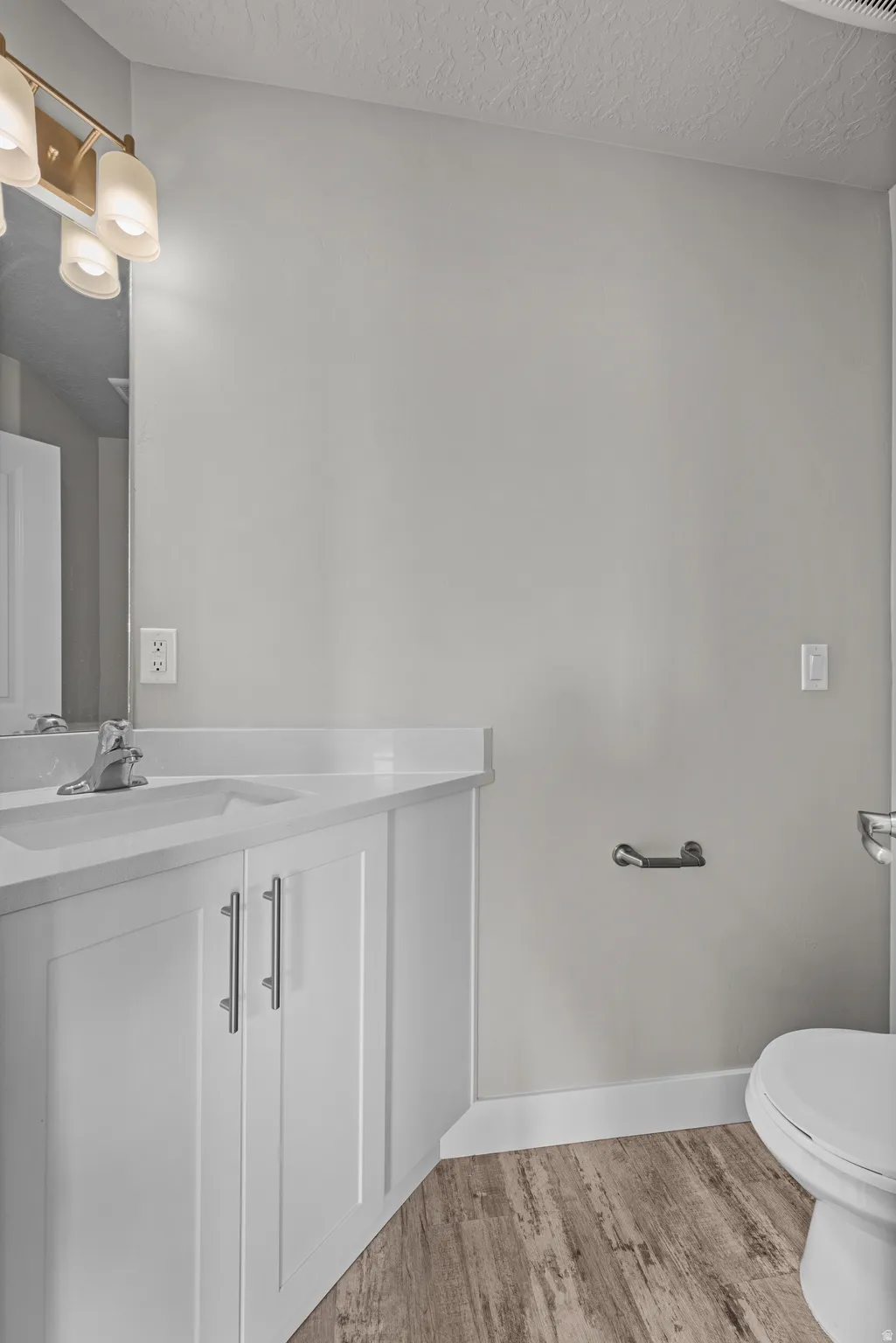 Bathroom with vanity, light wood-type flooring, and a textured ceiling