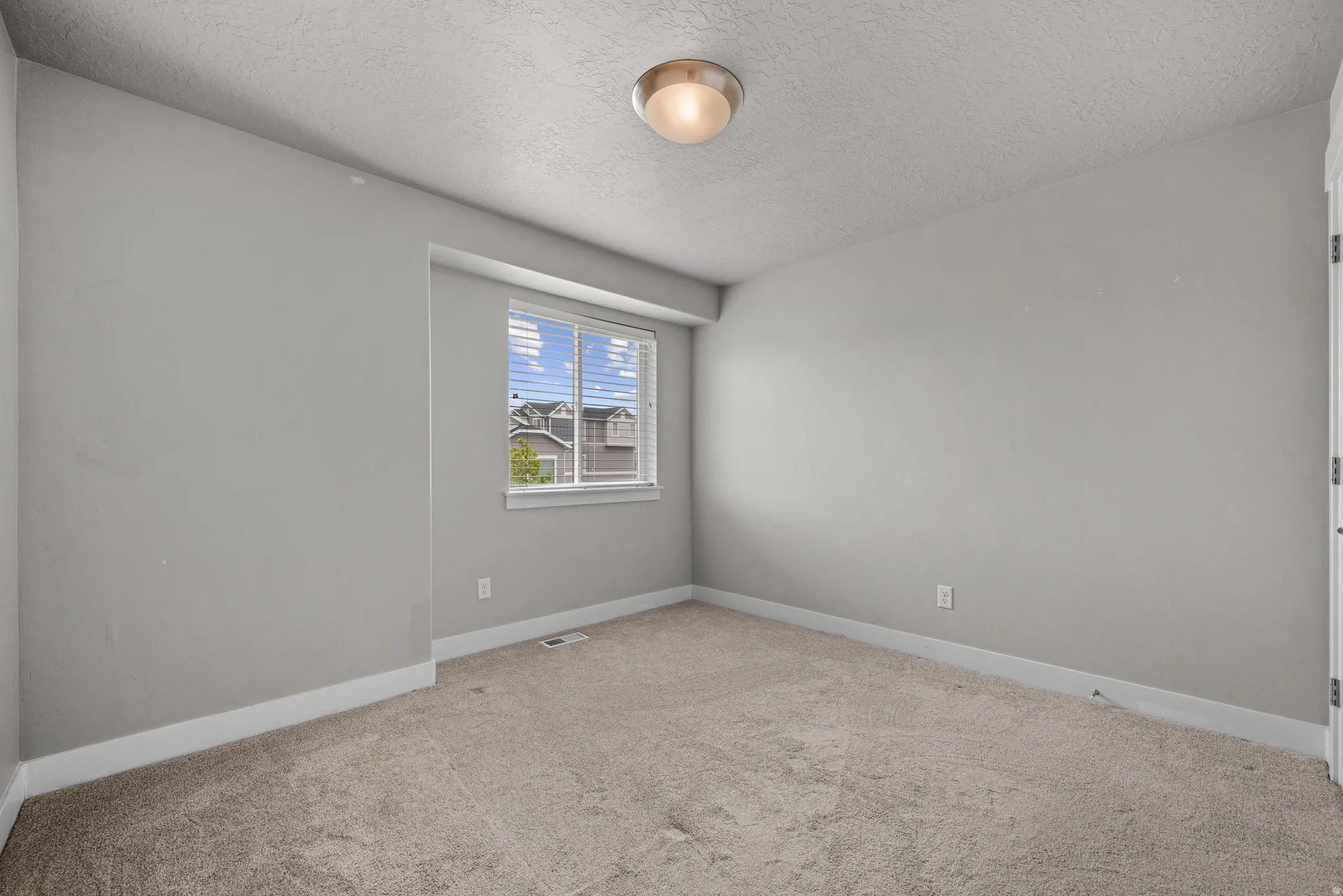 Empty room with carpet flooring and a textured ceiling