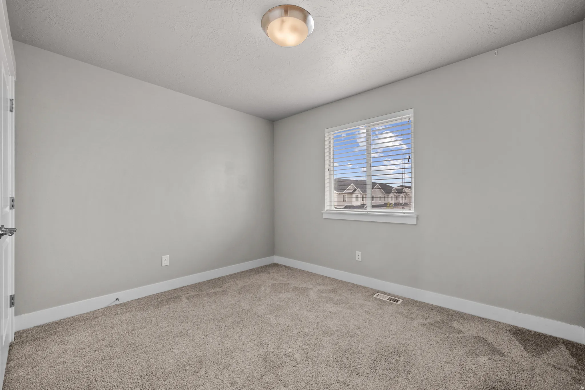 Unfurnished room featuring light carpet and a textured ceiling