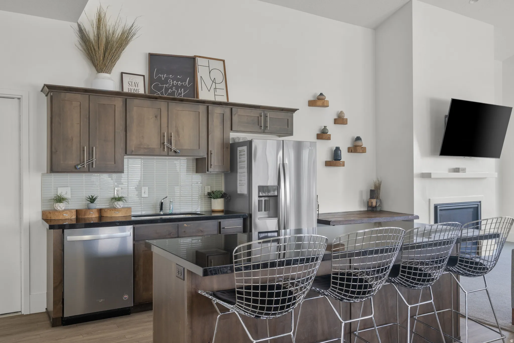 Kitchen featuring dark wood finish cabinets, stainless steel appliances, a breakfast bar area, and tasteful backsplash