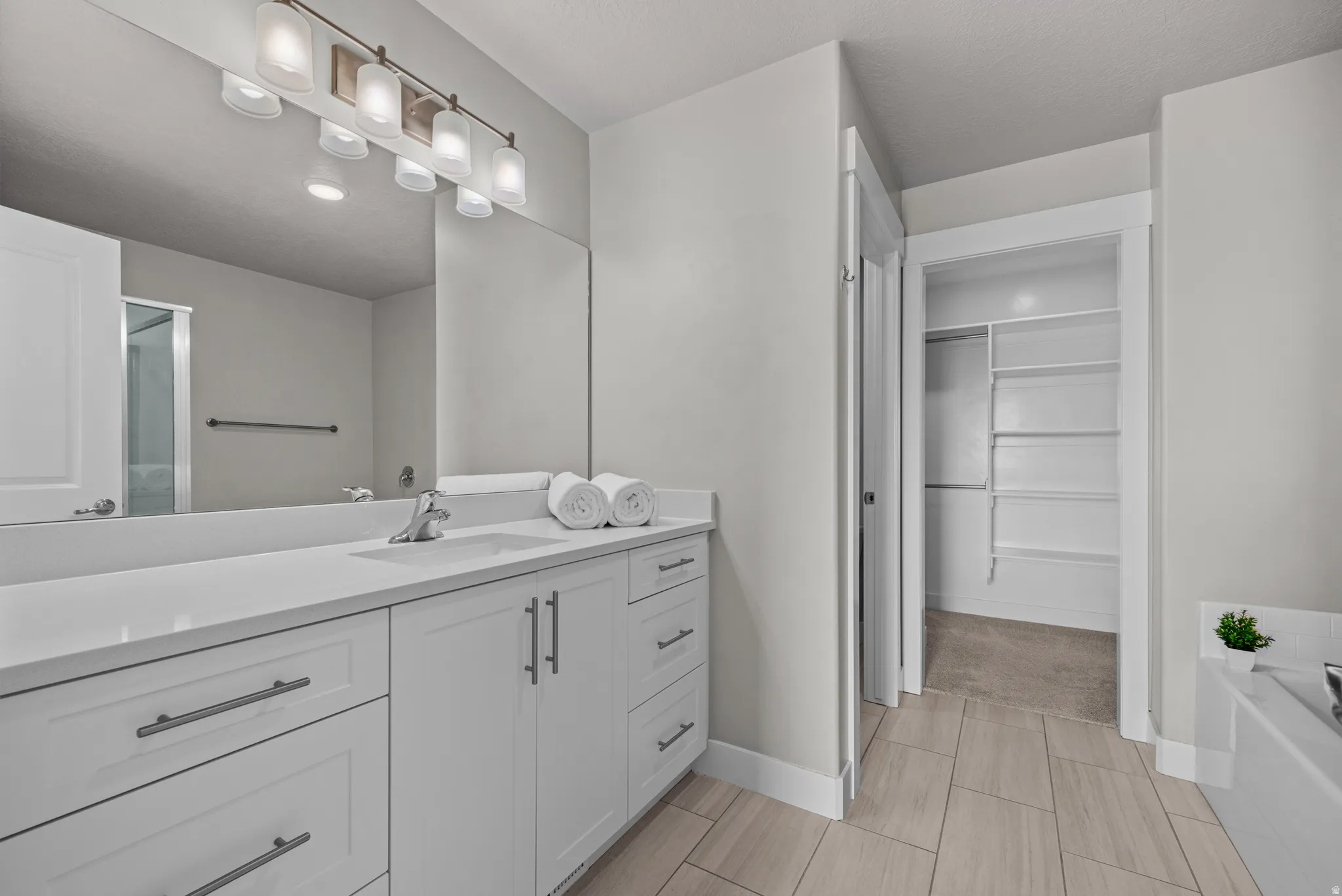 Bathroom with a spacious closet, vanity, a garden tub, and a shower with door