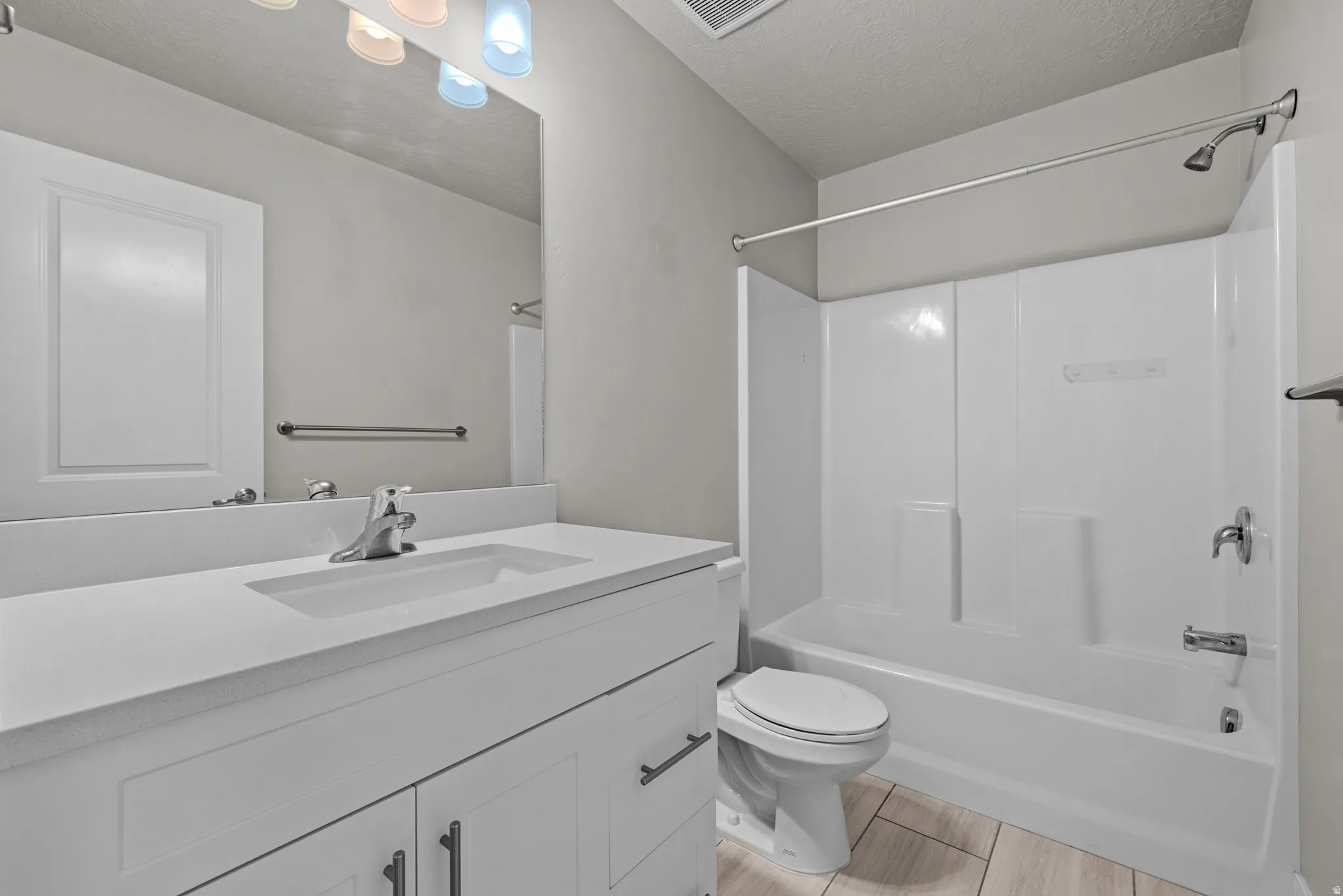 Bathroom with vanity,  shower combination, and a textured ceiling