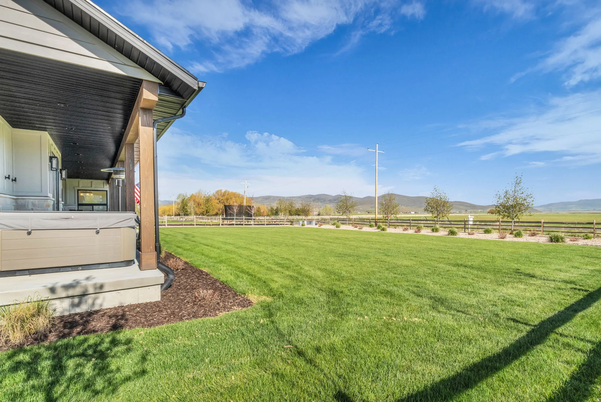 Expansive lawn area bordered by a wood fence, mature plantings, and distant mountains