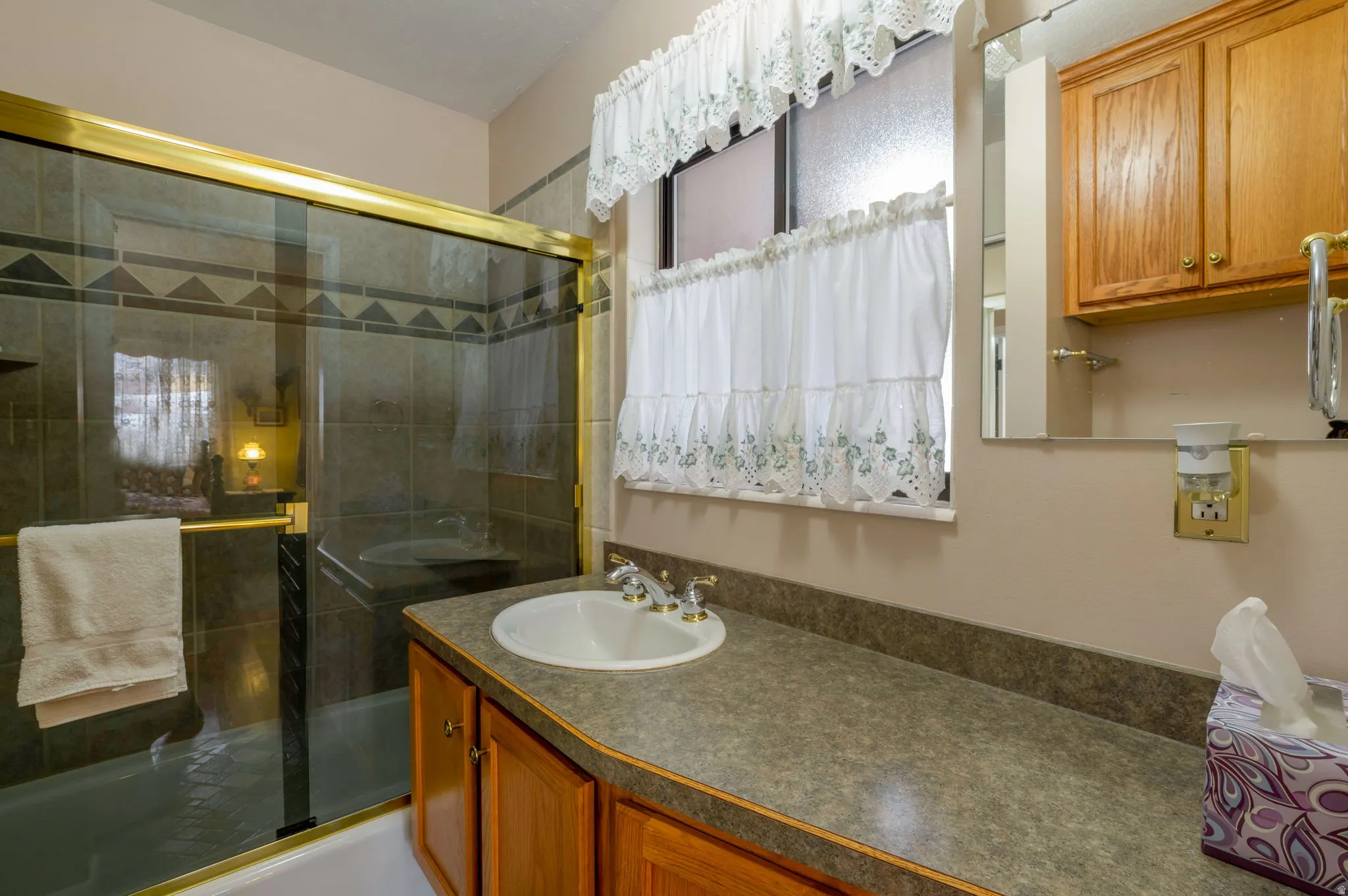 Bathroom with vanity and bath / shower combo with glass door