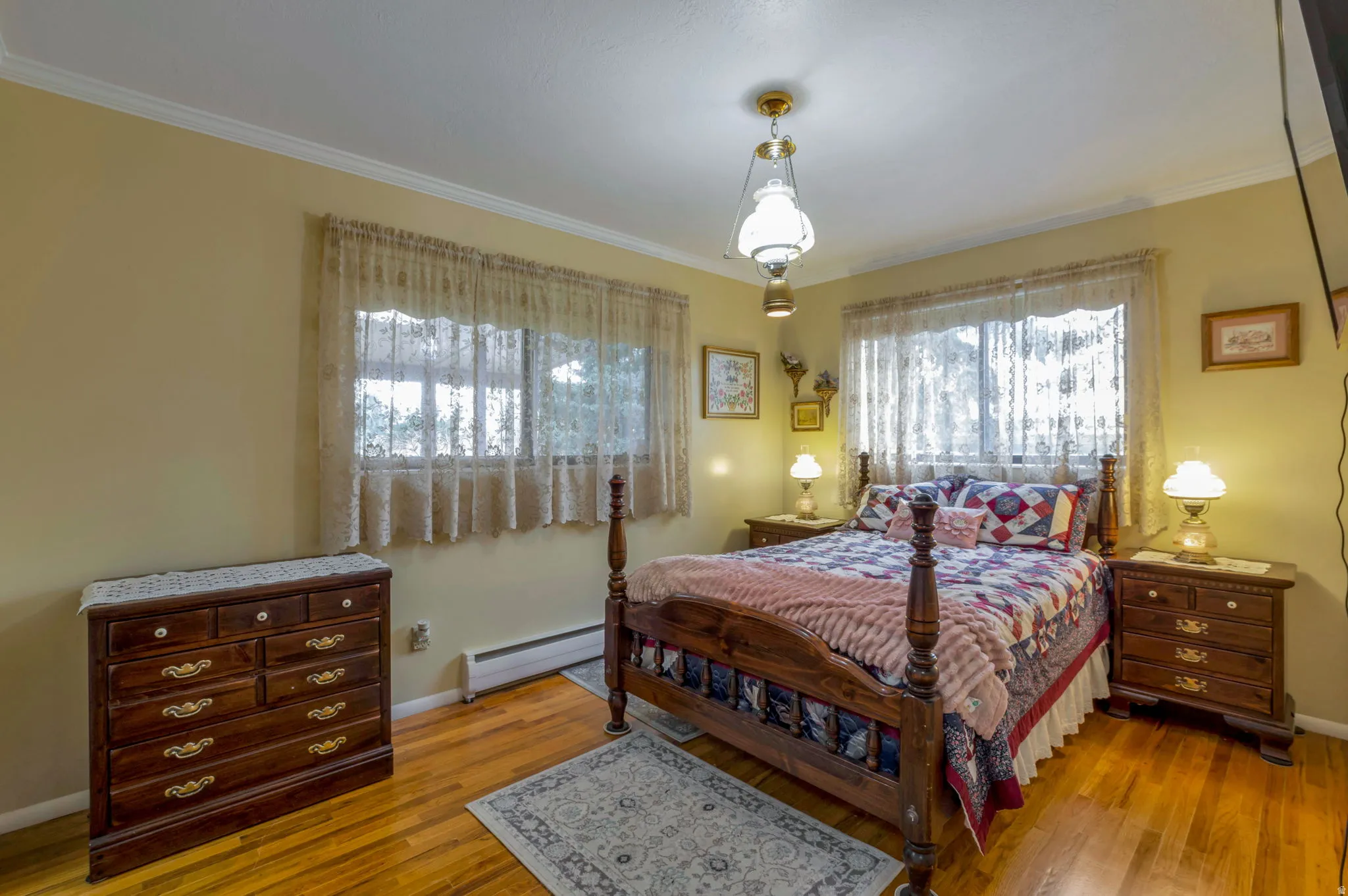 Bedroom featuring a baseboard radiator, wood-type flooring, and crown molding