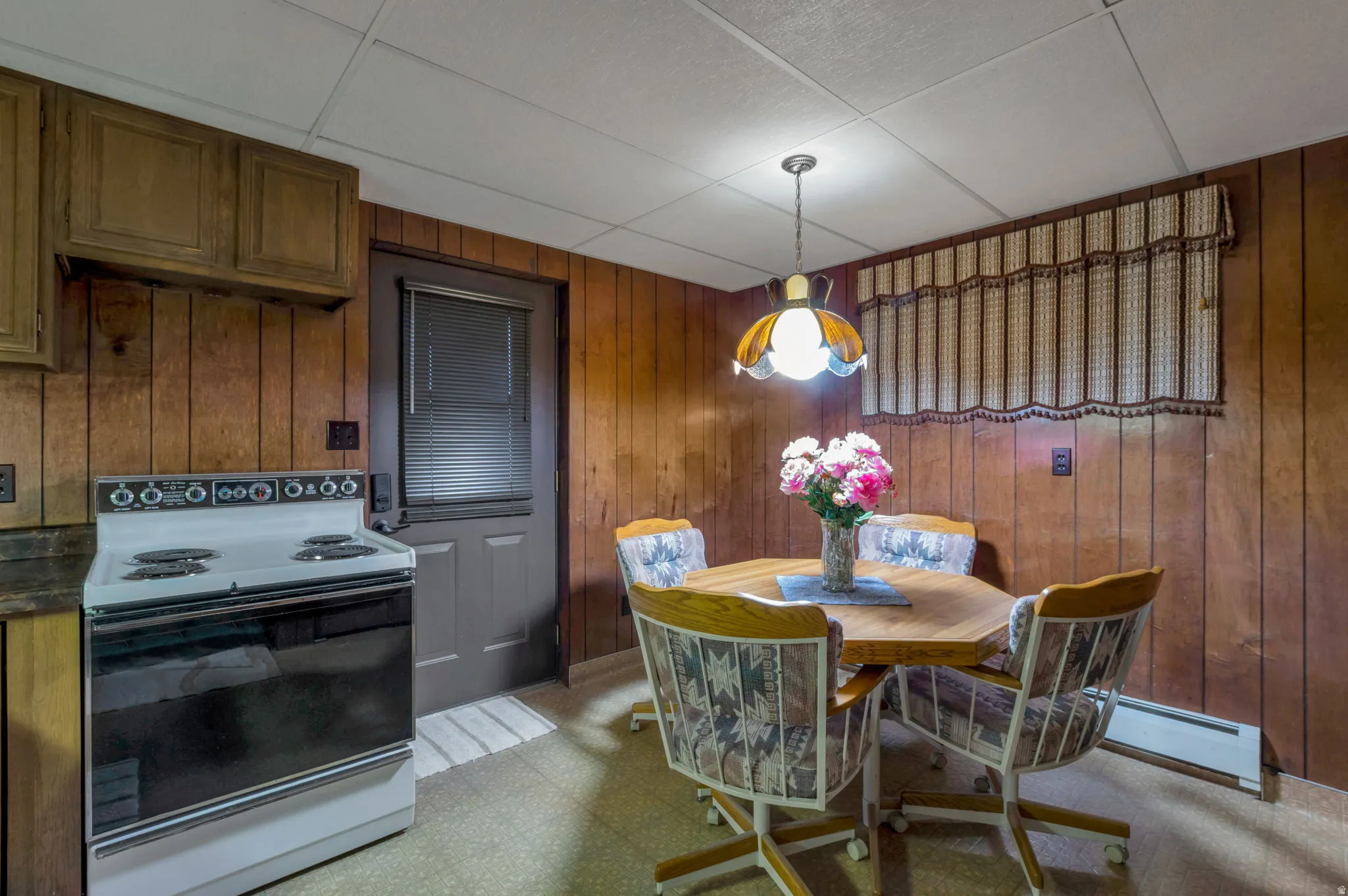 Dining room featuring light flooring, a baseboard radiator, and wood walls