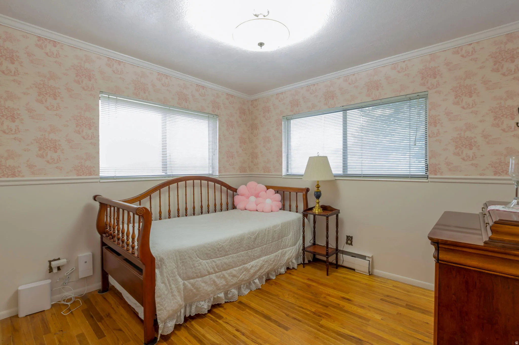 Bedroom featuring light wood finished floors, wallpapered walls, ornamental molding, and a baseboard radiator