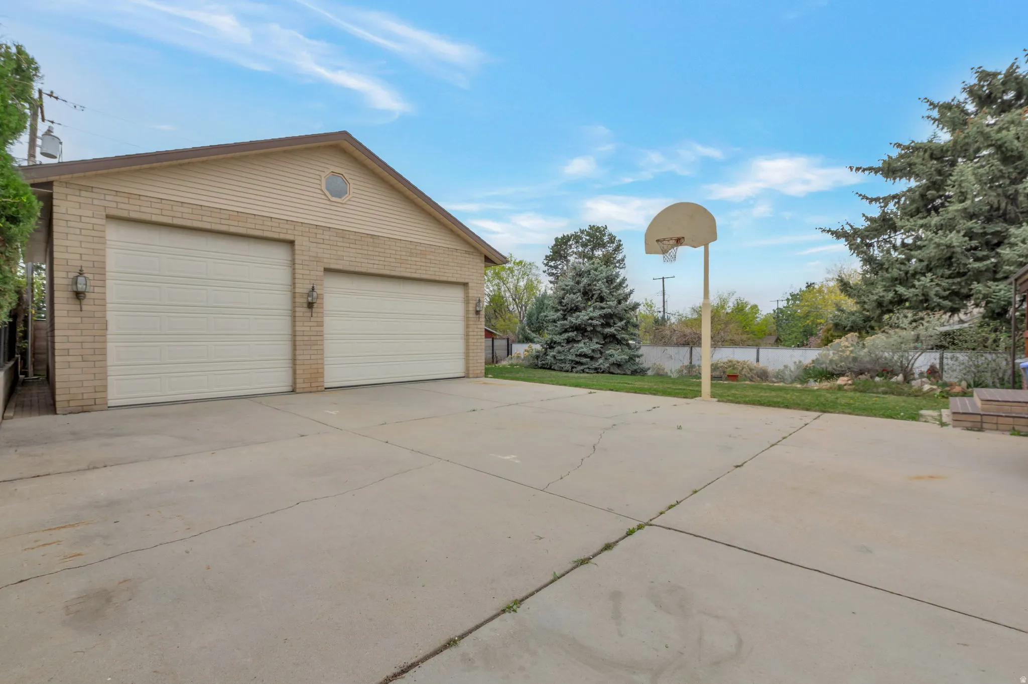 View of property exterior featuring a garage, brick siding, and an outbuilding