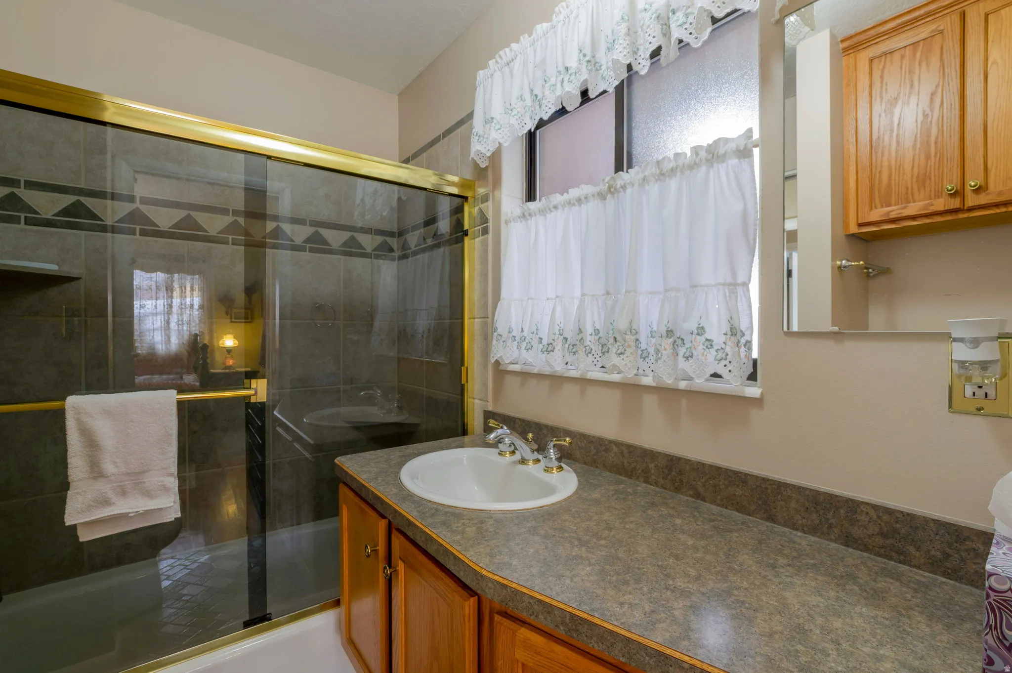Full bath featuring vanity and bath / shower combo with glass door