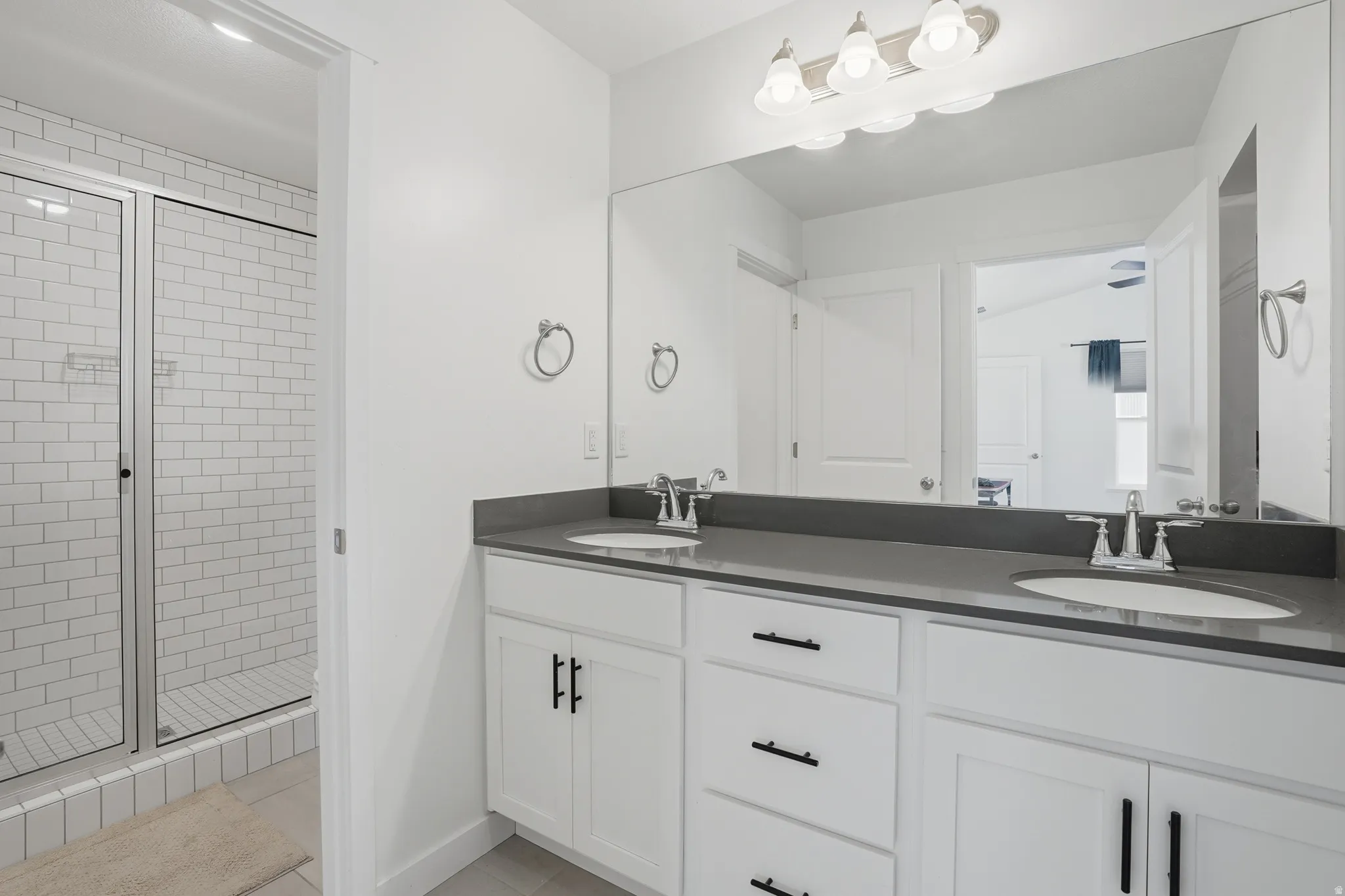 Full bath featuring double vanity with quartz tops and oversized  tile shower