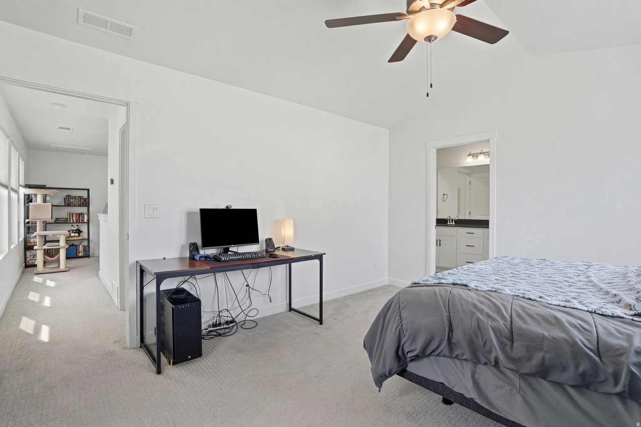 Primary bedroom featuring light carpet, an office area, ceiling fan, lofted ceiling, and connected bathroom