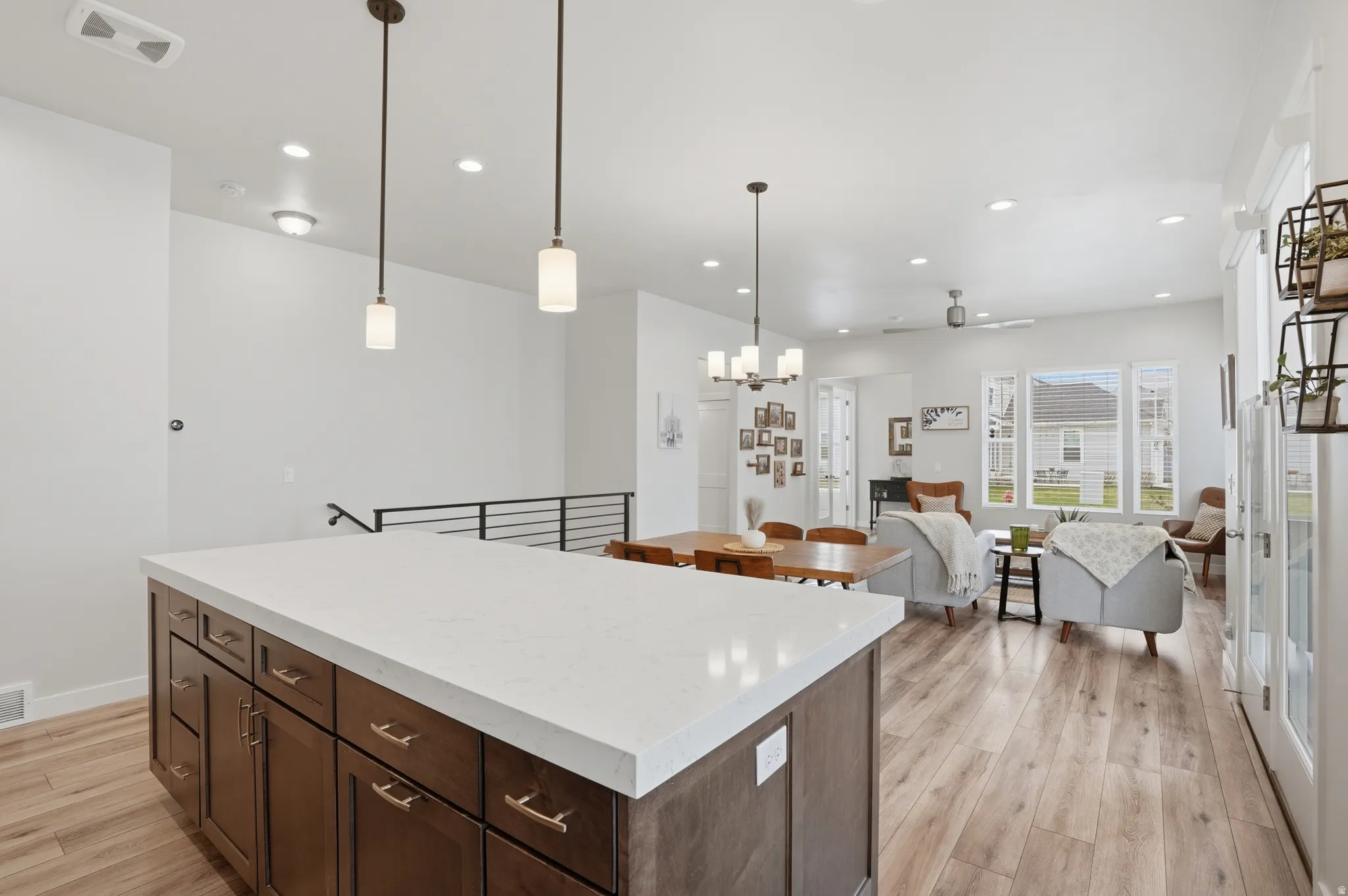 Kitchen featuring dark wood finish cabinets, light wood-style flooring, a center island, open floor plan, and light stone countertops