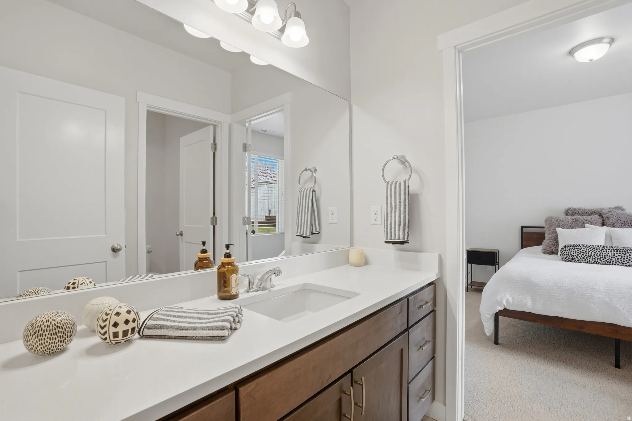 Ensuite bathroom featuring vanity and light colored carpet