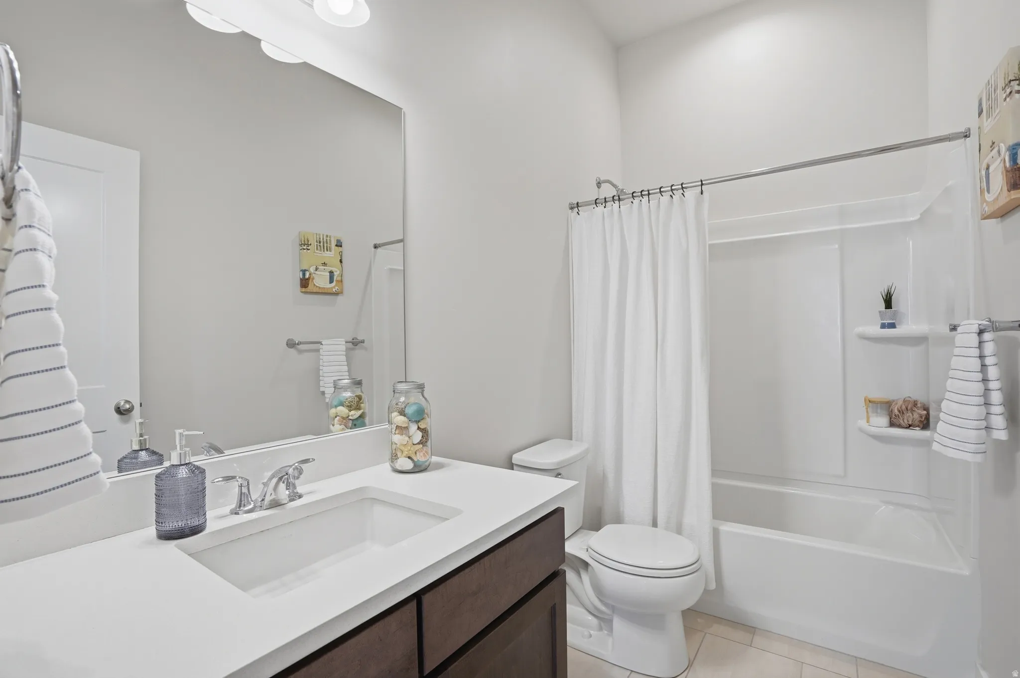 Bathroom featuring vanity, shower / tub combo with curtain, and light tile patterned floors
