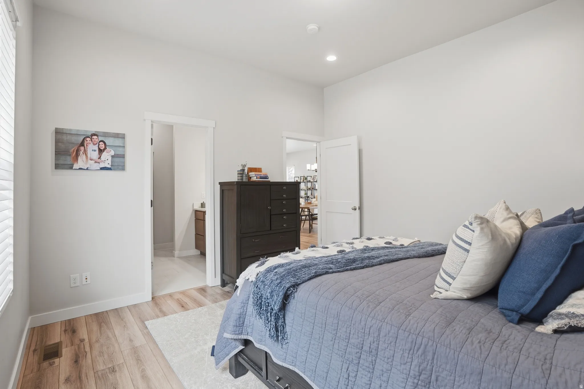 Bedroom with light wood finished floors, recessed lighting, and ensuite bath