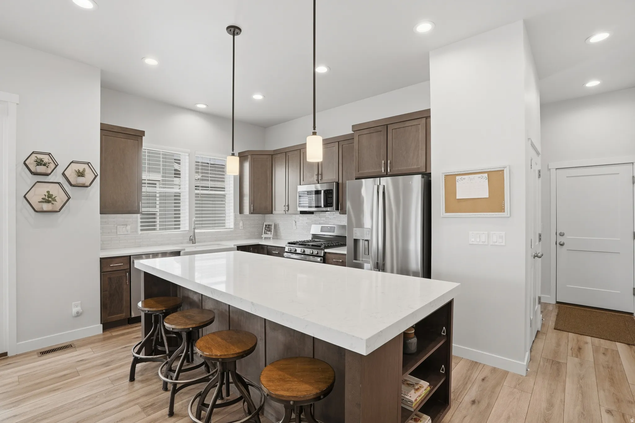 Kitchen with stainless steel appliances, light wood-style floors, a kitchen bar, and tasteful backsplash
