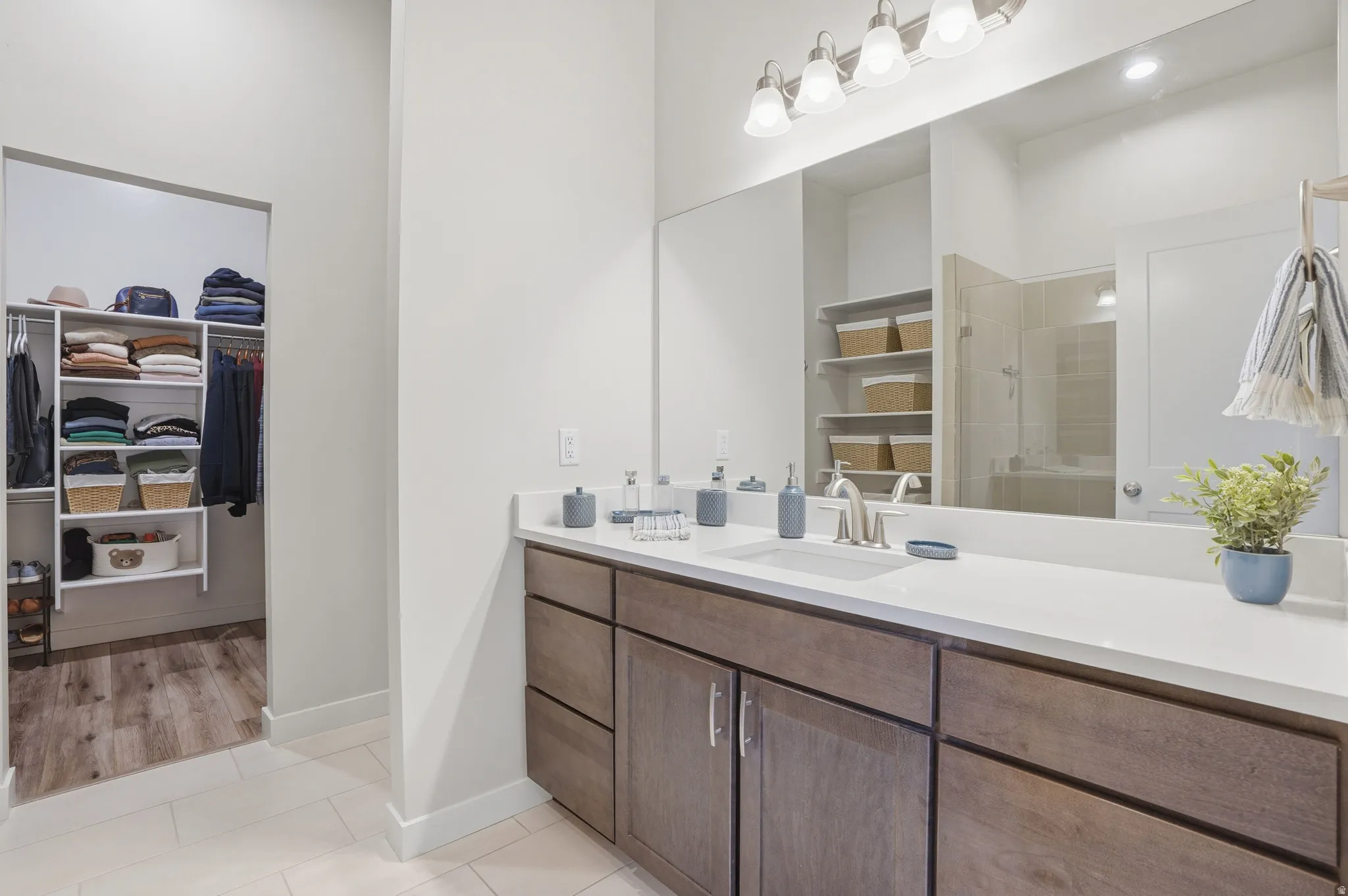 Full bath featuring vanity, light tile patterned floors, a spacious closet, and a stall shower