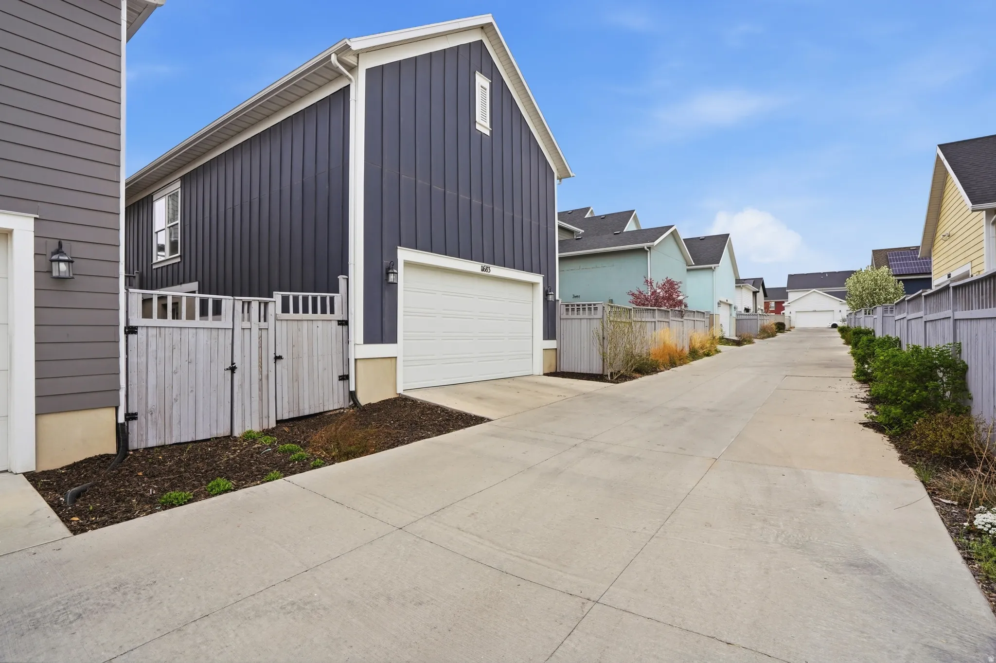 View of home's exterior with a gate, board and batten siding, concrete driveway, and a residential view