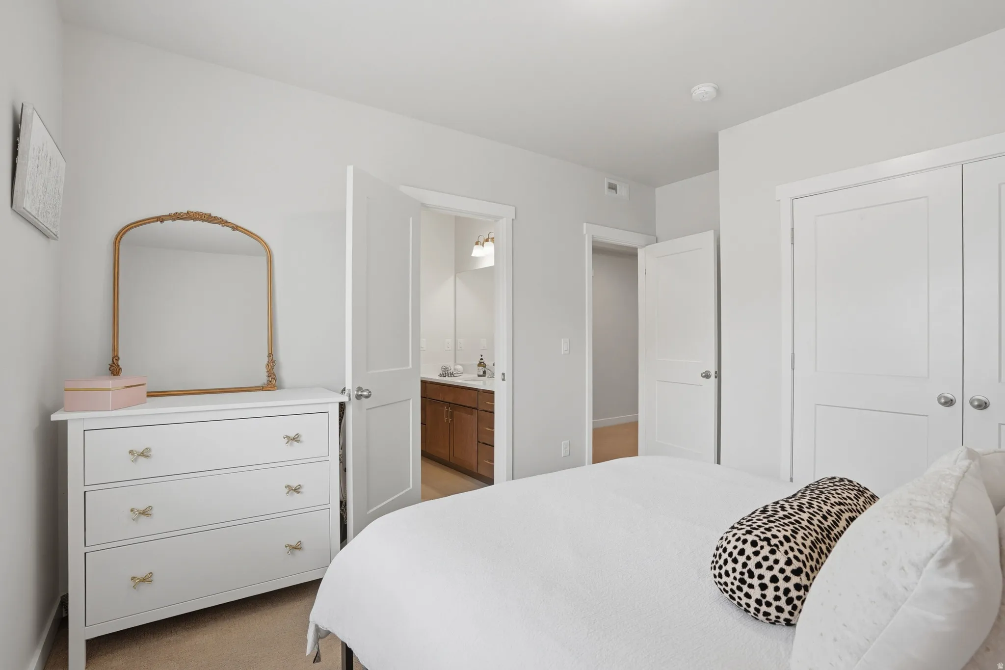 Bedroom with light colored carpet, a closet, and connected bathroom