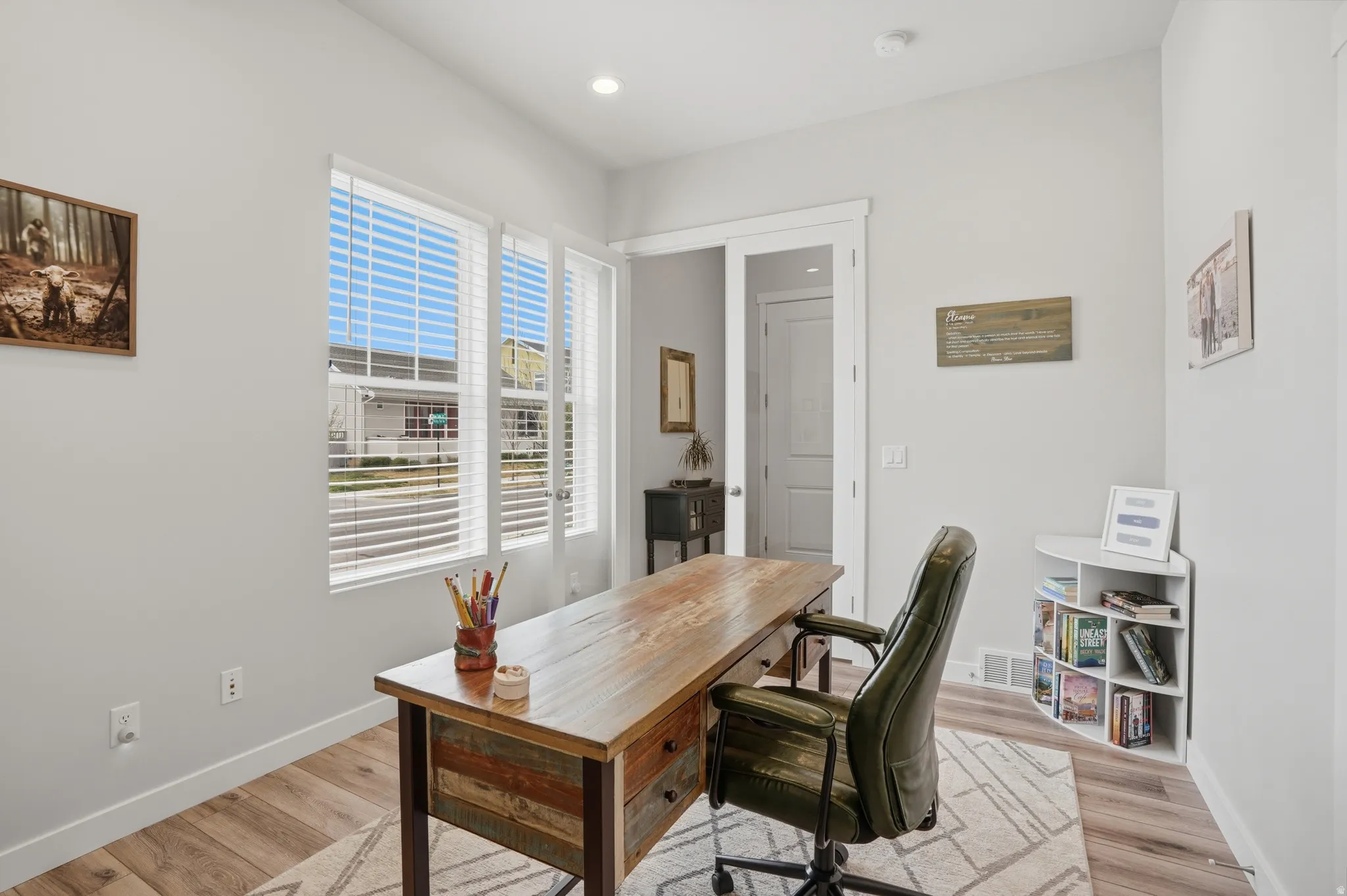 Office with light wood-type flooring and recessed lighting
