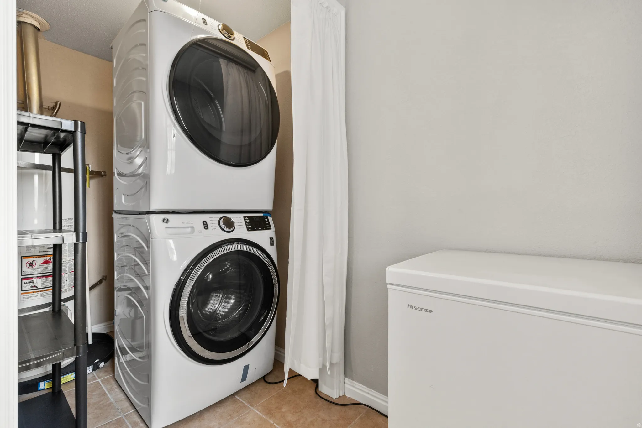 Laundry area with light tile patterned floors and stacked washer / dryer