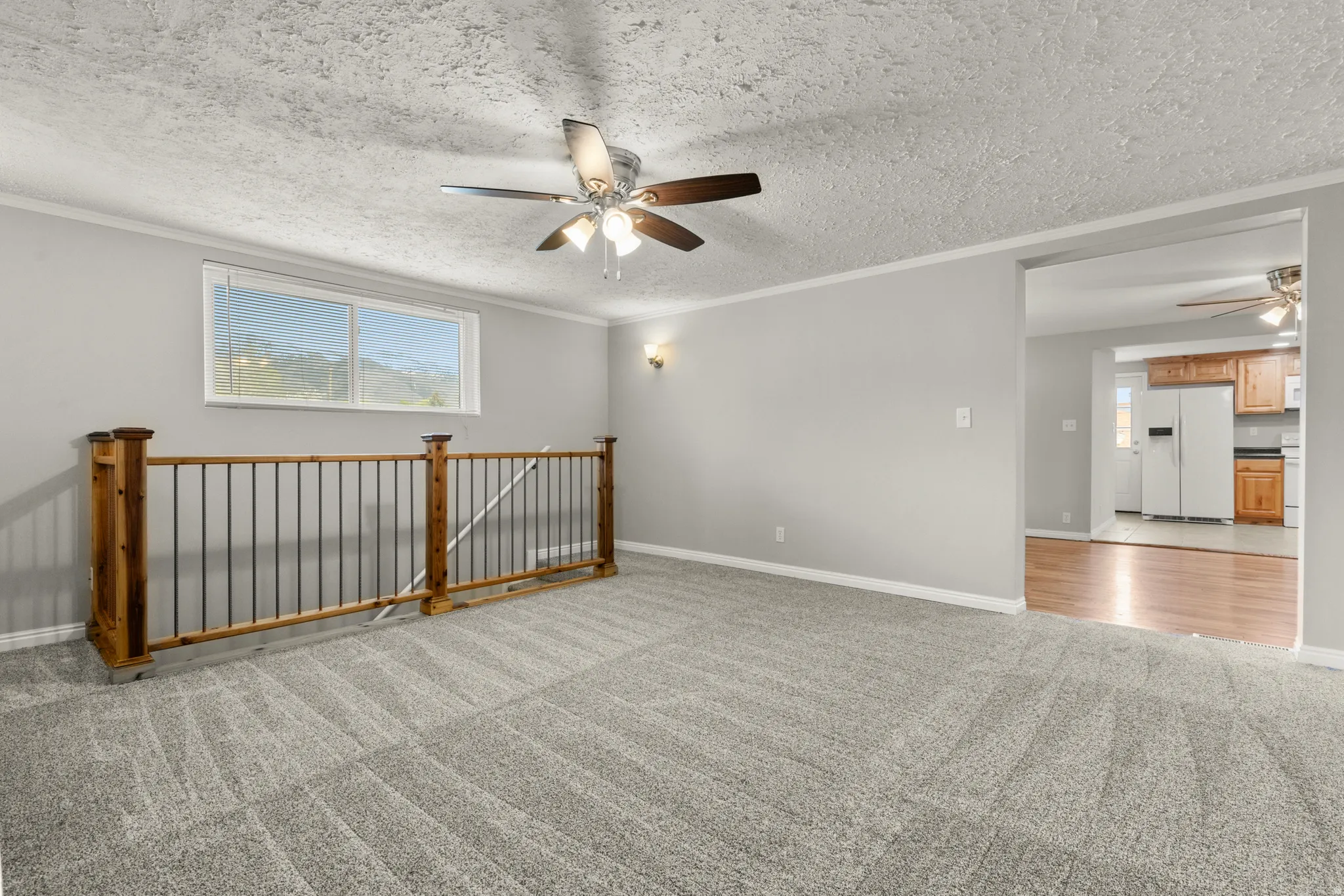 Spare room featuring ceiling fan, light colored carpet, a textured ceiling, ornamental molding, and plenty of natural light