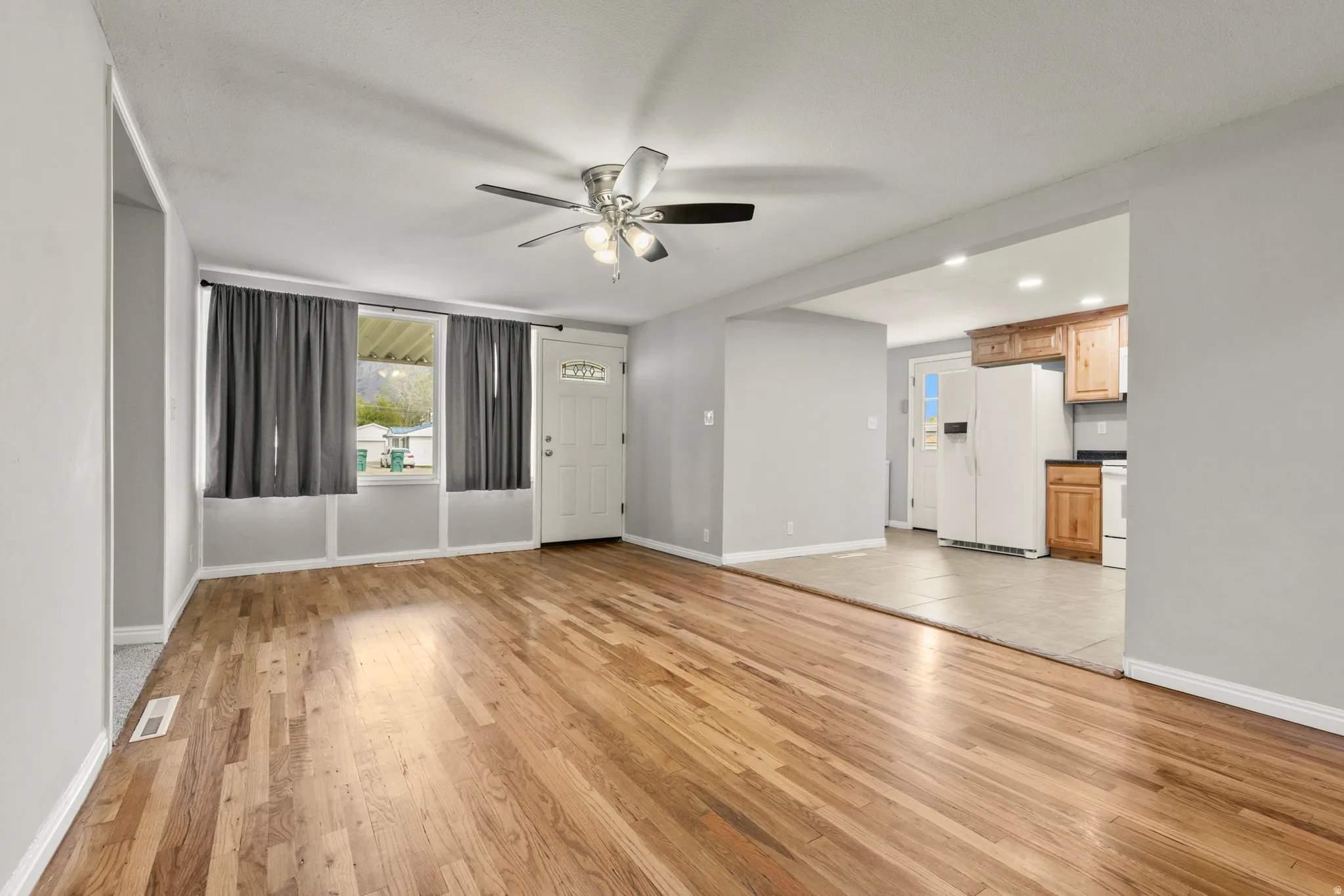 Unfurnished living room featuring light wood-style floors, a ceiling fan, and recessed lighting