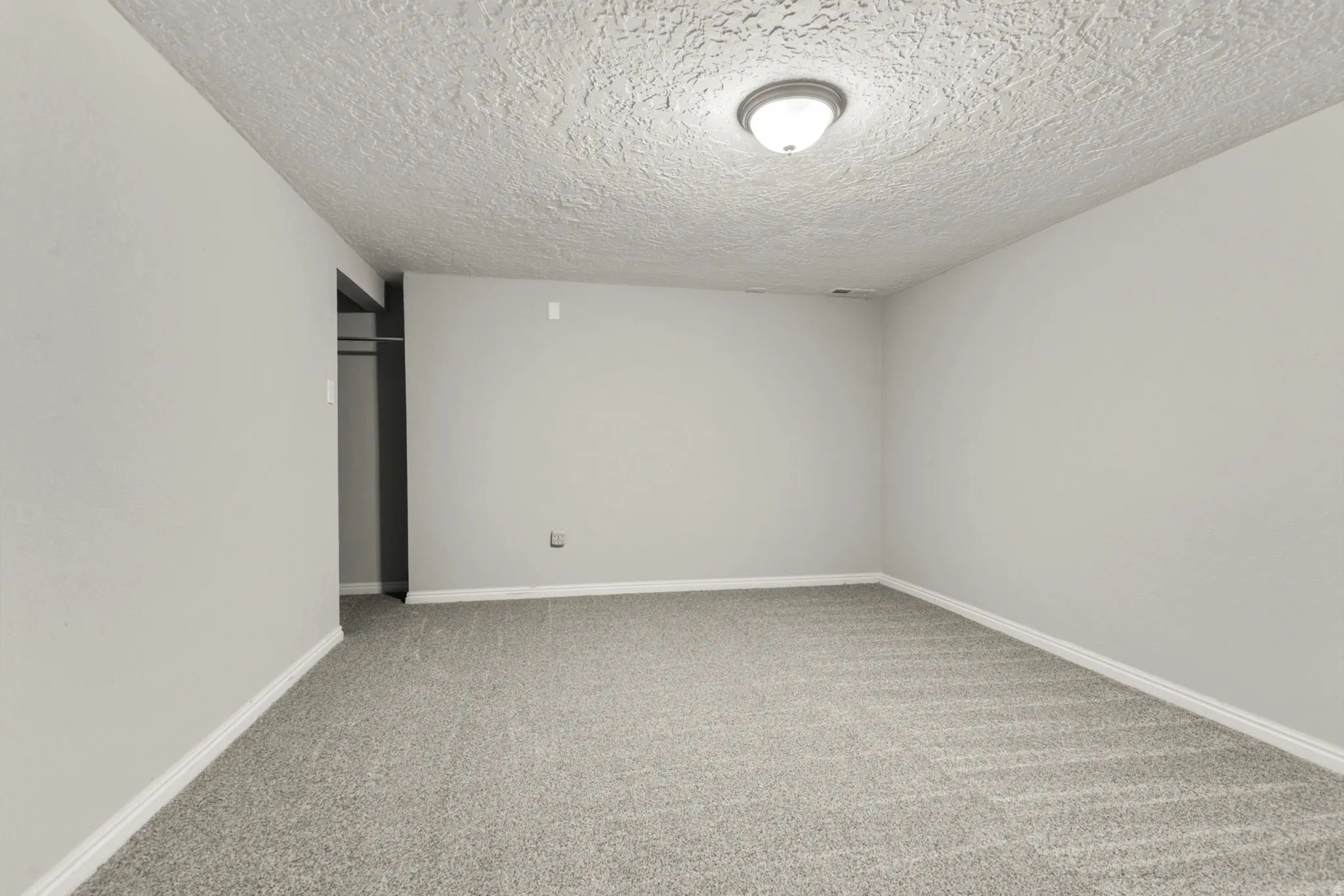 Unfurnished room with light carpet and a textured ceiling