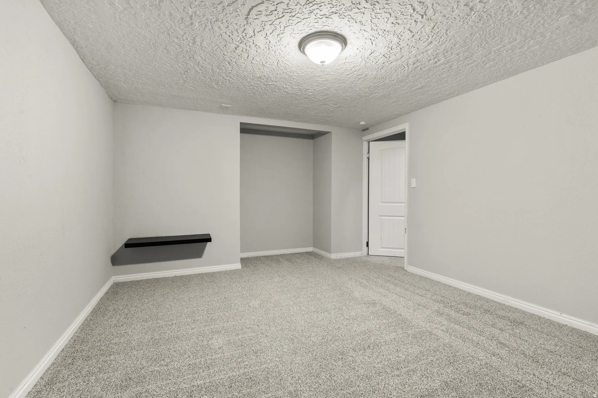 Empty room with a textured ceiling and light colored carpet