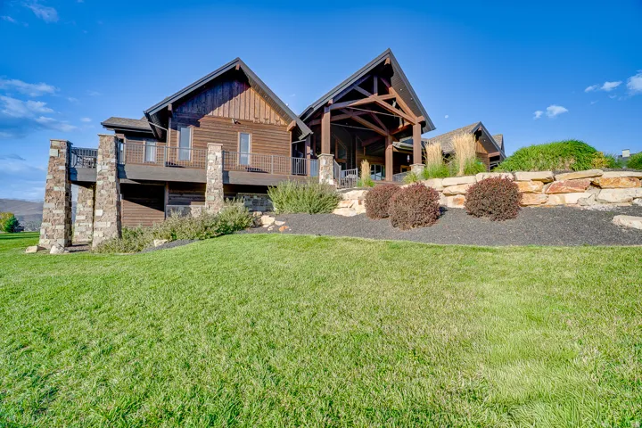 Back of house with board and batten siding, a lawn, and a patio area