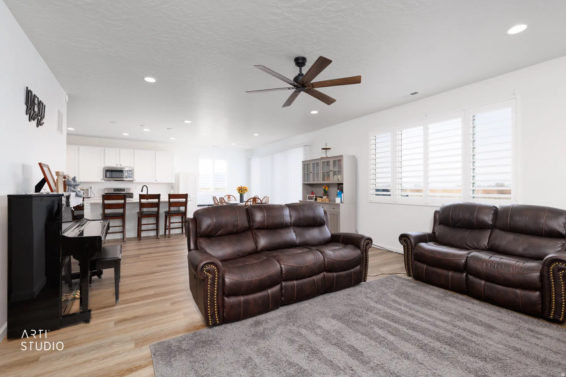 Living area with light wood-type flooring, a ceiling fan, recessed lighting, and a textured ceiling