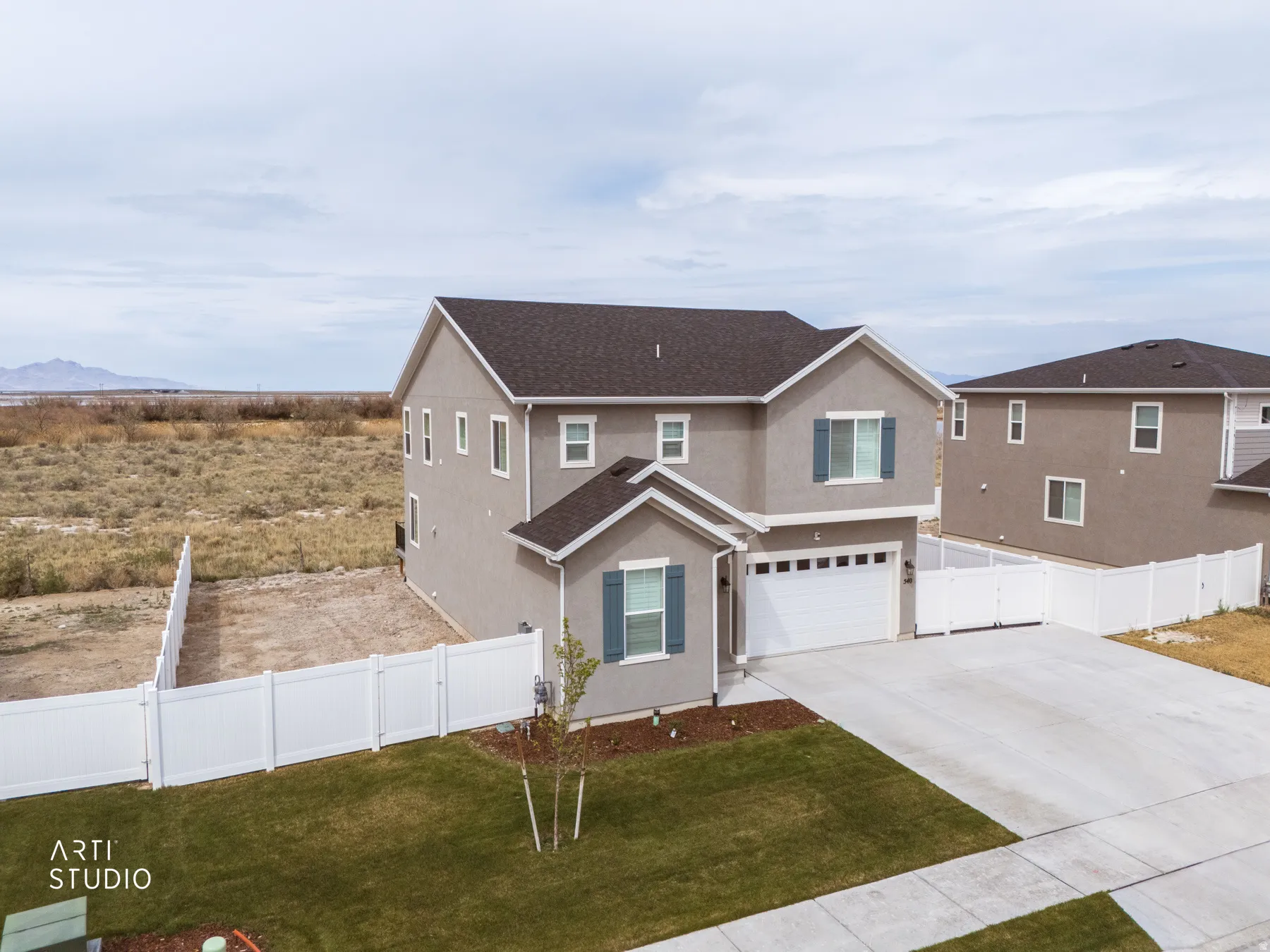 Traditional home with a gate, a garage, driveway, stucco siding, and a shingled roof