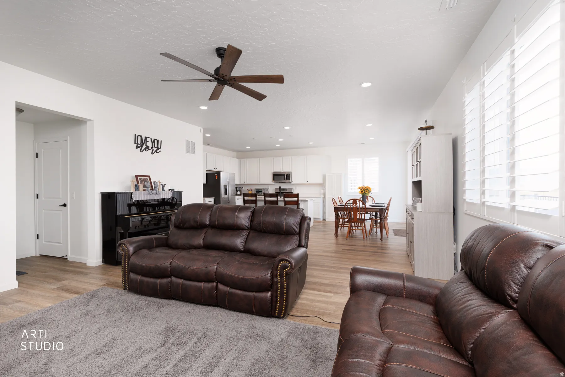 Living room featuring ceiling fan, light wood-type flooring, recessed lighting, and a textured ceiling