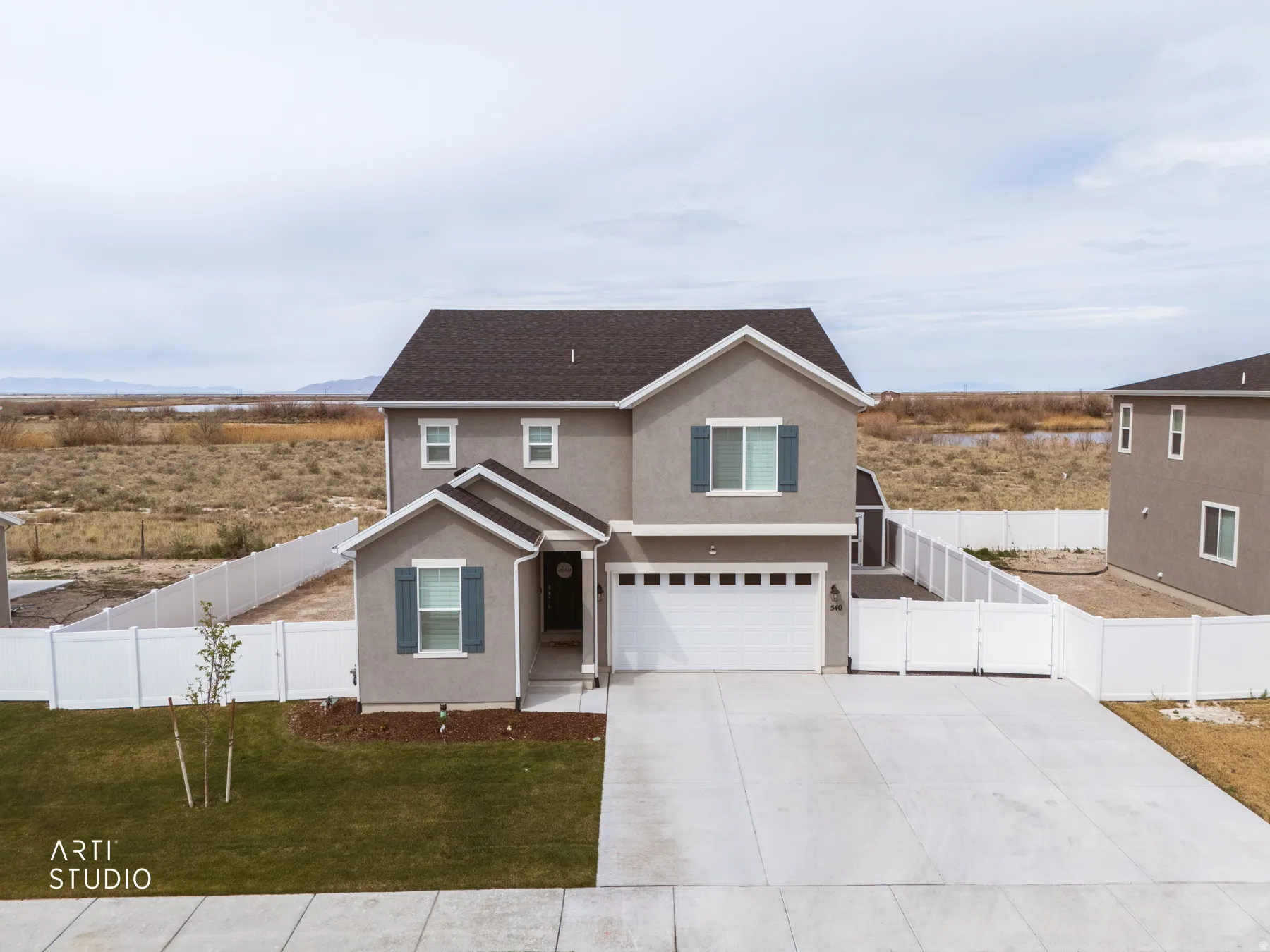 Traditional home featuring an attached garage, stucco siding, driveway, and a gate