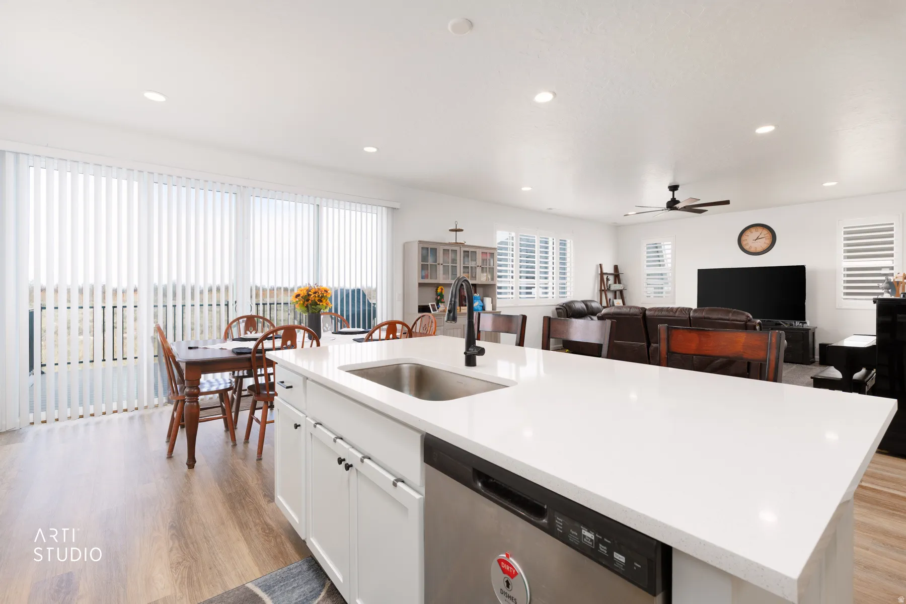 Kitchen with dishwasher, a center island with sink, light wood-style flooring, open floor plan, and light stone countertops