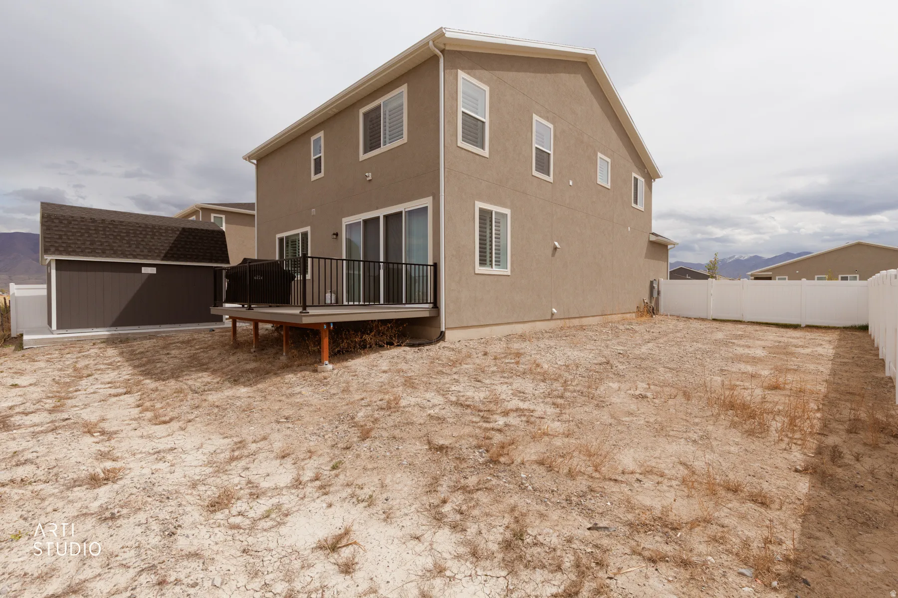 Back of property with a deck, a storage unit, a fenced backyard, and stucco siding