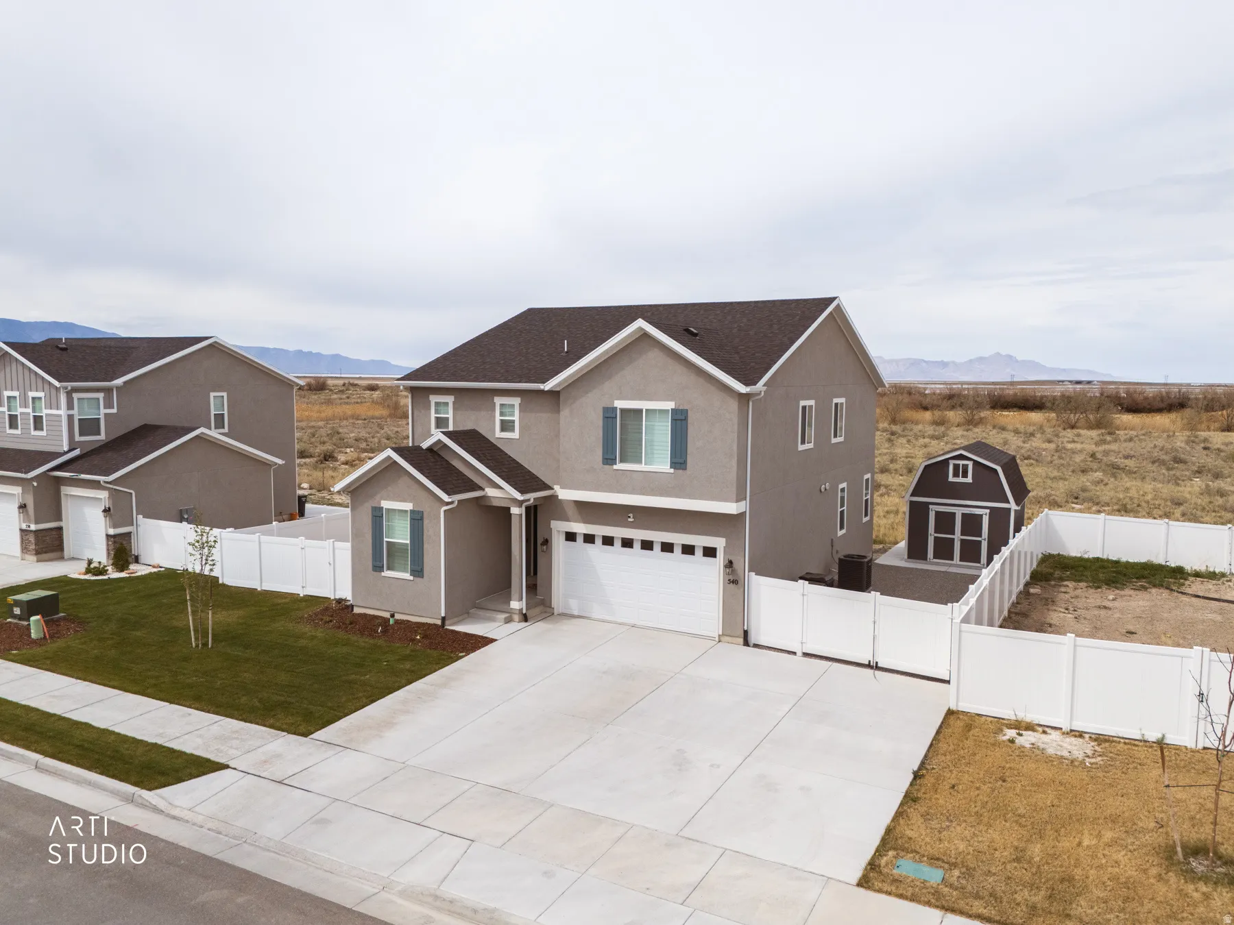 Traditional-style house with a garage, concrete driveway, stucco siding, a mountain view, and a gate