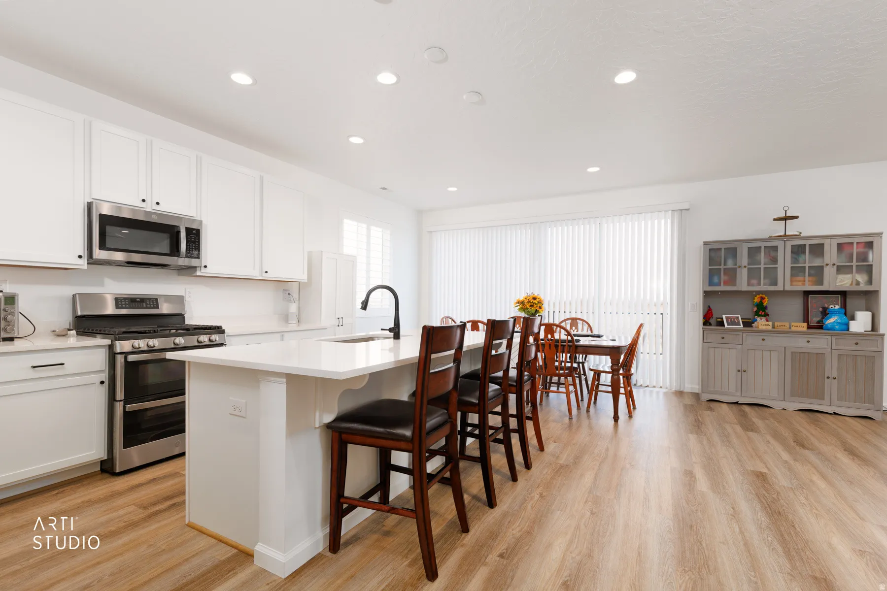 Kitchen with a breakfast bar, stainless steel appliances, a center island with sink, light wood-type flooring, and recessed lighting