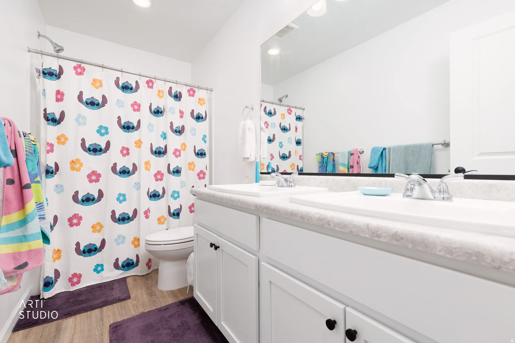 Full bathroom featuring double vanity, light wood-style flooring, curtained shower, and recessed lighting